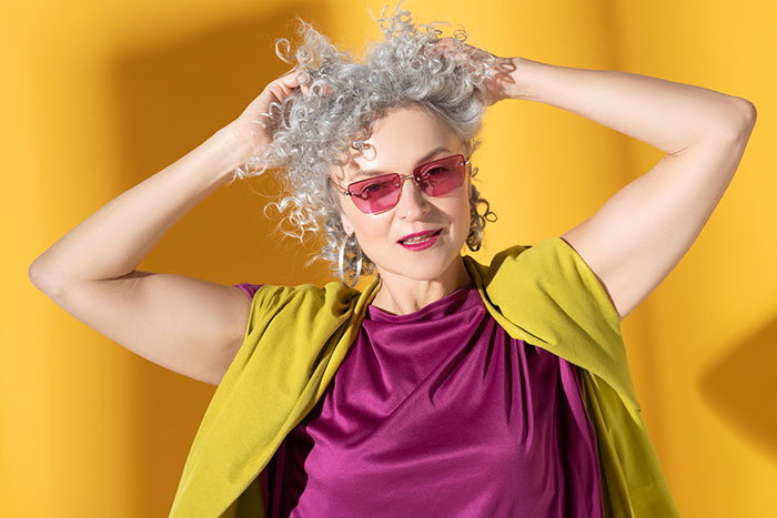 Woman in pink sunglasses and colorful outfit poses against a yellow background. Stepmom K-pop character, kid's birthday. Woman in pink sunglasses and colorful outfit poses against a yellow background. Stepmom K-pop character, kid's birthday.