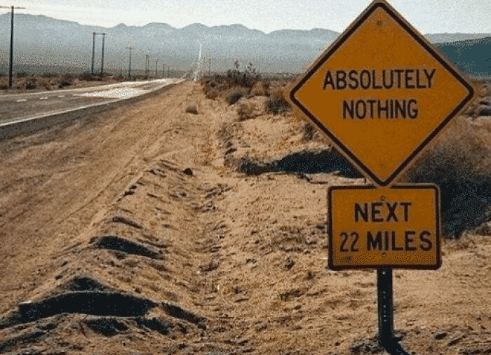 A desert road with a sign saying Absolutely Nothing Next 22 Miles, showcasing one of the USA's wildly different places.