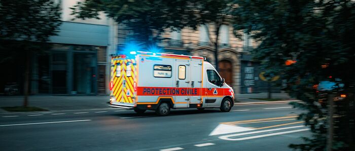 An ambulance speeding down a city street, its lights flashing, capturing a moment from one of the babysitting stories.