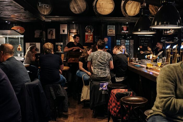 People enjoying drinks in a dimly lit bar, setting a scene for a potential terrifying "we need to leave now" moment.