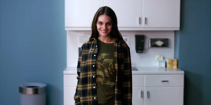 A smiling woman with a sinister gaze stands in a clinical room, a chilling image from terrifying horror movies.