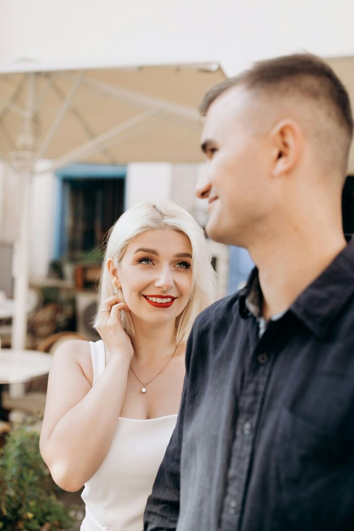 A blonde woman looking up at a man with a slight smile, possibly anticipating or reacting to mansplaining examples.