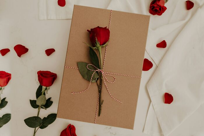 A brown gift box with a single red rose and petals, symbolizing moments of realizing the problem.