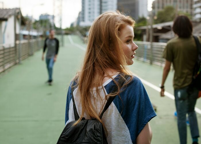 A young woman with a backpack looking over her shoulder, reflecting on moments of realizing she is the problem.