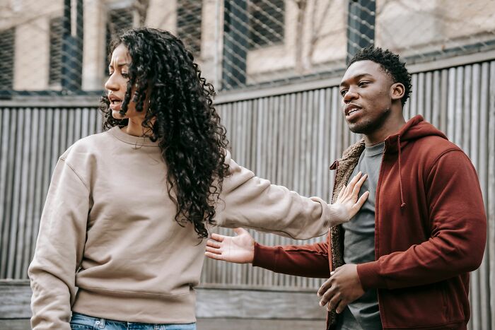 A man and a woman in an outdoor setting, where the woman is pushing the man away, realizing she is the problem.