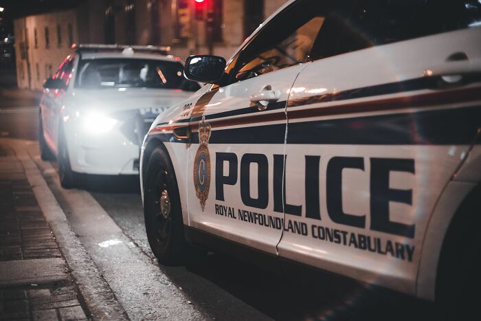Two police cars on a street at night, highlighting moments when people realized they are the problem.