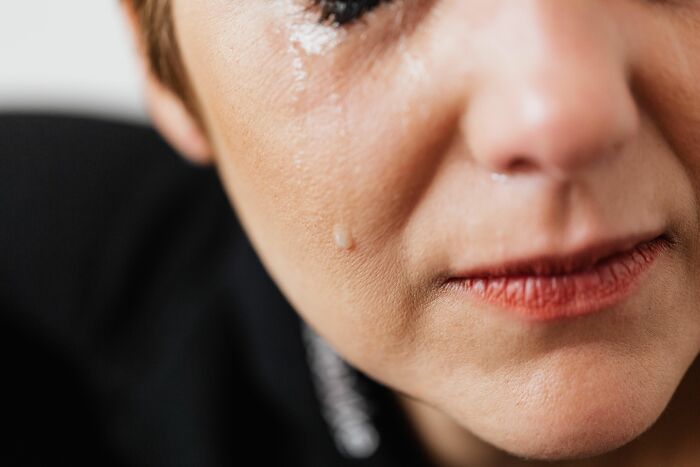 A close-up of a woman's face with a tear rolling down her cheek, realizing she is the problem.