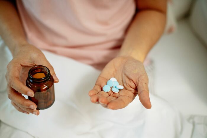 Hands holding pills and a bottle, realizing they are the problem.