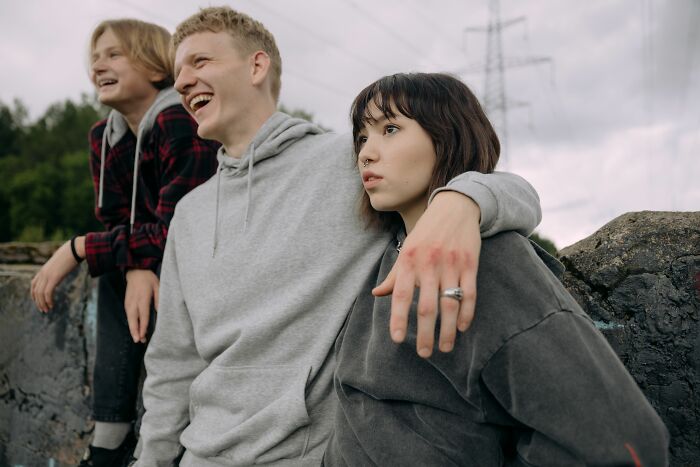 Friends realizing they are the problem, one laughing while another looks away.