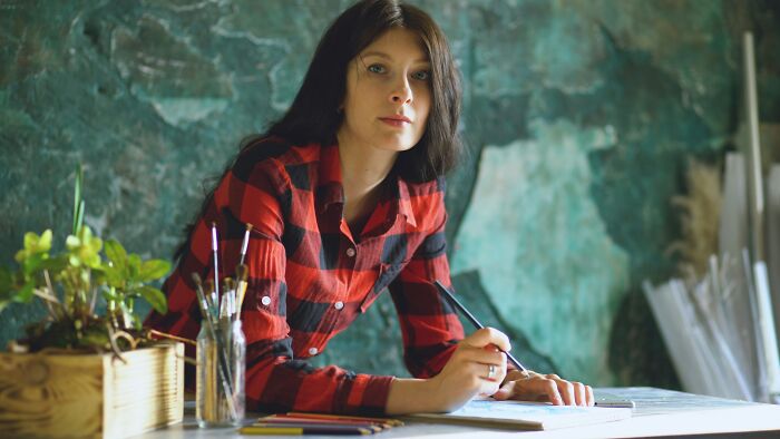 Woman in a plaid shirt painting, focusing on individual passions before getting married.