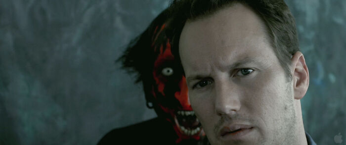 A man looking scared with a red-faced demon behind him, highlighting the most terrifying horror movies.