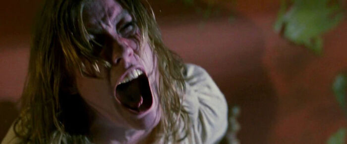 A woman with disheveled hair screams in terror, a classic scene from one of the most terrifying horror movies.