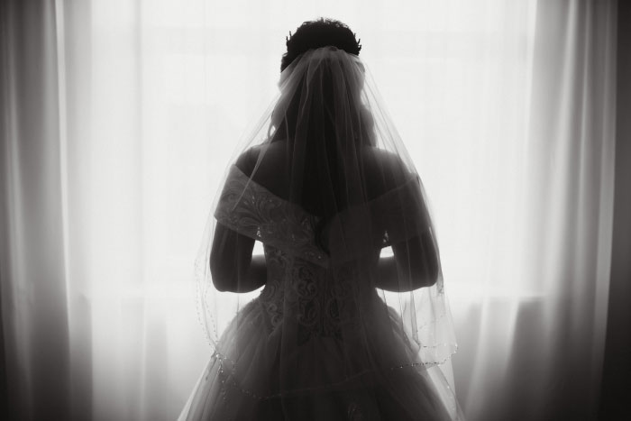 Bride in silhouette by a window, contemplating the worst things at a wedding.