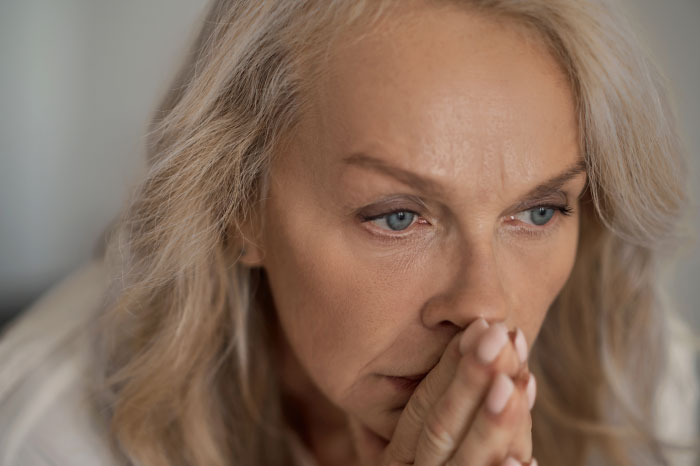 A close-up of a worried woman with blonde hair, reflecting the chaotic emotions of a wedding event.