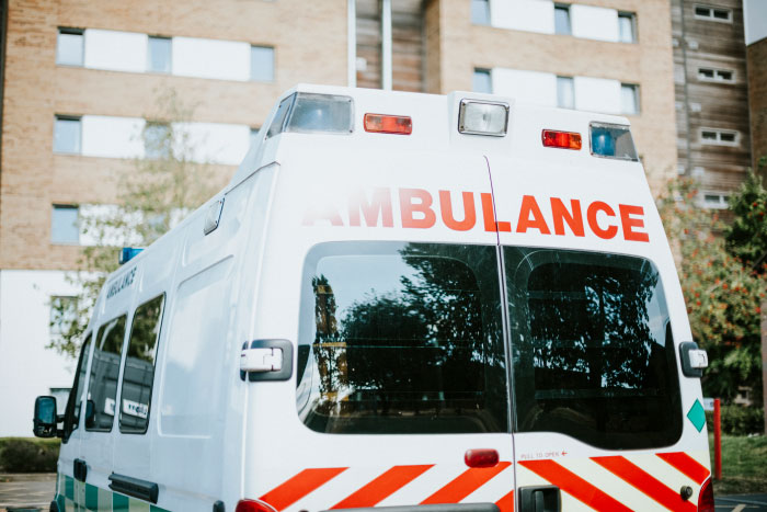 A close-up of the back of a white ambulance with red letters, signaling a chaotic wedding event.