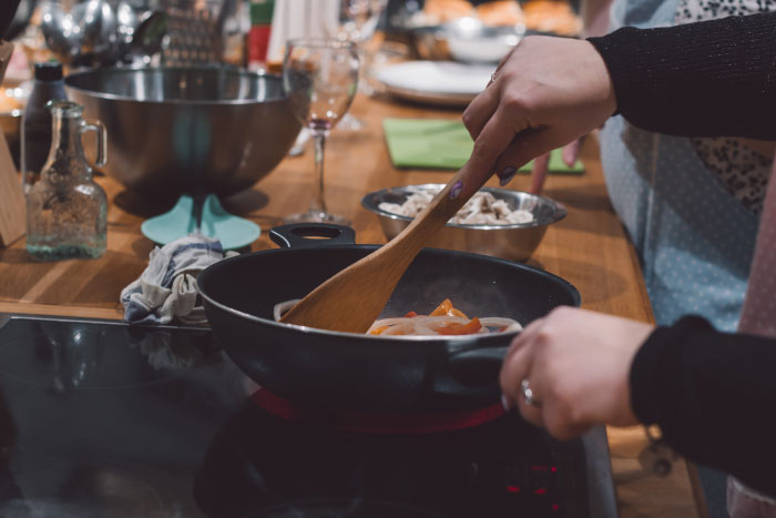 Hands stirring vegetables in a pan, a chaotic scene sometimes seen at a wedding.