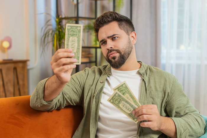 A man holding money, looking displeased, after a wedding was canceled. A man holding money, looking displeased, after a wedding was canceled.