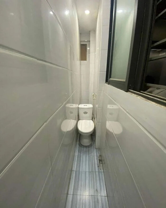 A narrow bathroom with two toilets side-by-side, a prime example of a construction fail in space utilization.