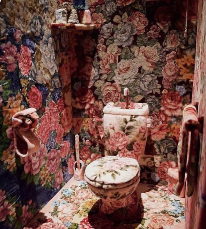 A bathroom completely covered in floral carpet, including the toilet and sink, demonstrating a significant construction fail.