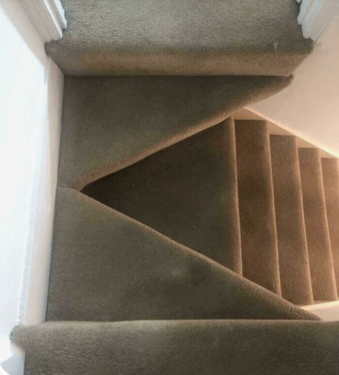 A carpeted staircase with an oddly shaped, triangular landing, an example of construction fails.