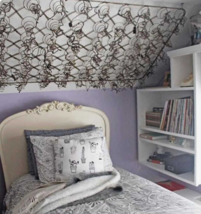 A bed with a mattress spring frame hanging from the ceiling, an example of construction fails.