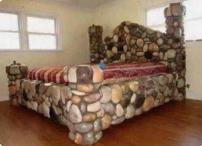 A bed frame made entirely of river stones, showcasing a bizarre construction fail.