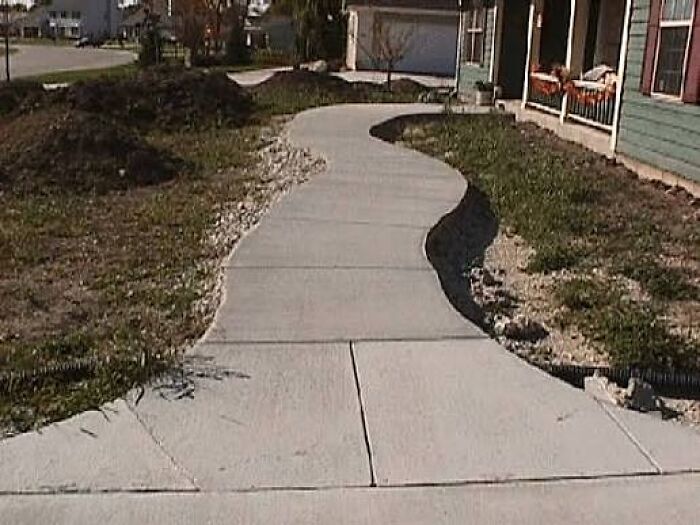 A wavy concrete sidewalk leading to a house, an instance of unusual construction fails.