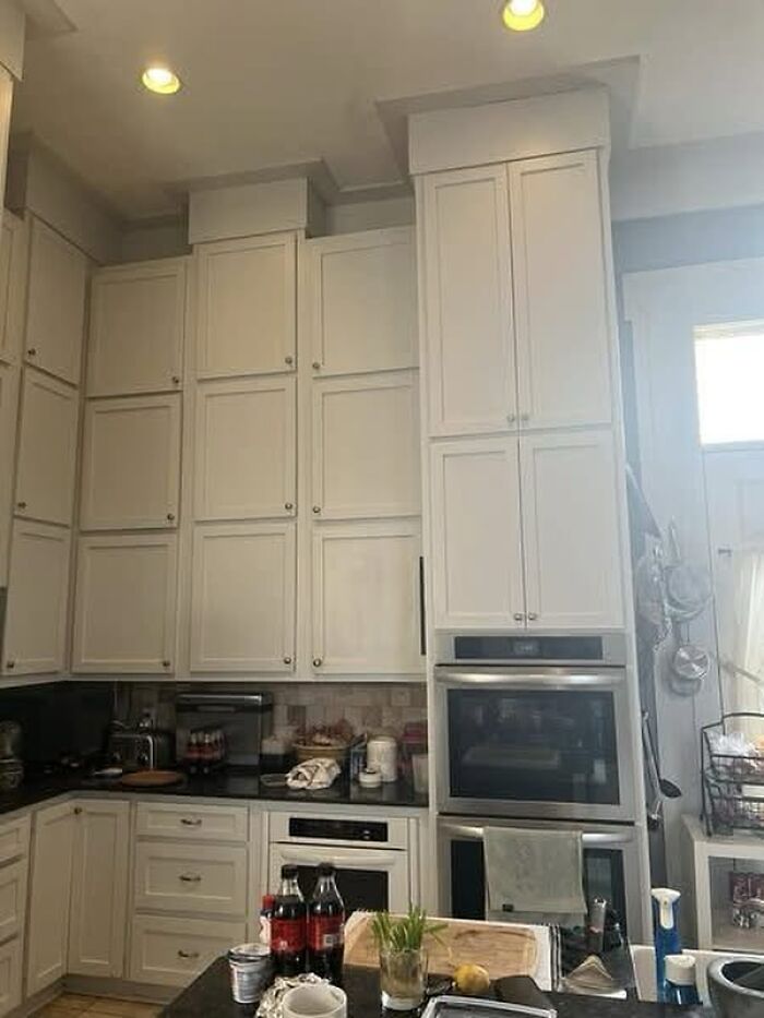 A kitchen with mismatched cabinet heights and an oven stacked unusually high, exemplifying construction fails.