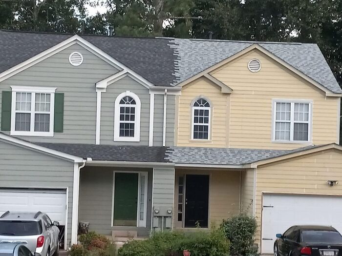 A duplex house with a roof half finished with gray shingles and half with light gray shingles, a clear construction fail.