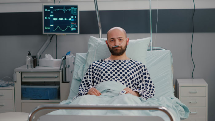 A man with cancer looks horrified in a hospital bed as his postpartum wife expects him to slog at home.