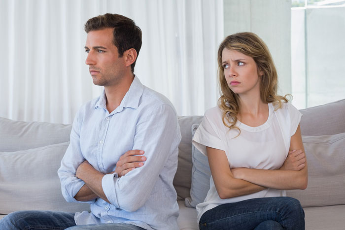 A man and his postpartum wife sit apart, looking away. He is horrified that she expects him to slog at home despite his cancer.