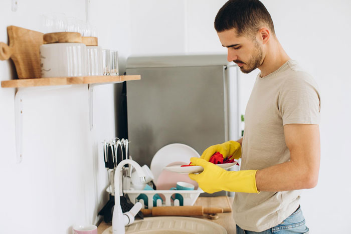 A man in yellow gloves doing dishes, while his postpartum wife expects him to slog at home despite his cancer.