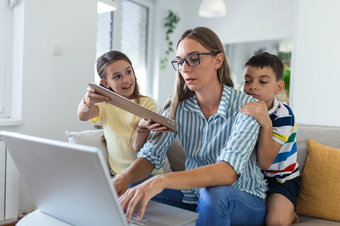 A tired wife on a laptop with two children, showing the reality check of having kids she never wanted.