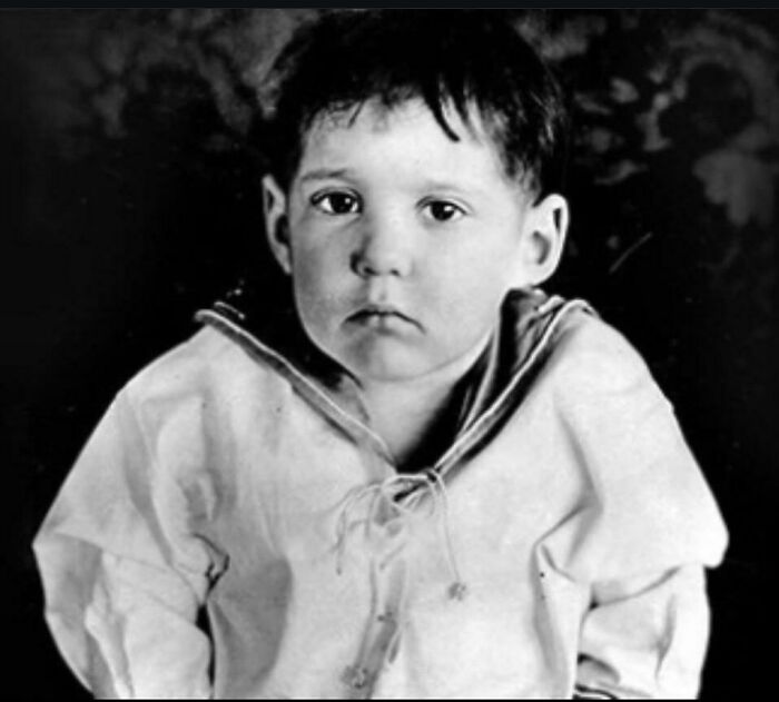 Black and white portrait of a young boy in a sailor top, looking sad, sharing coolest history facts.