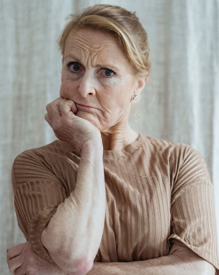 An older woman with a pensive expression, possibly reflecting on her daughter-in-law's decision not to have grandbabies.