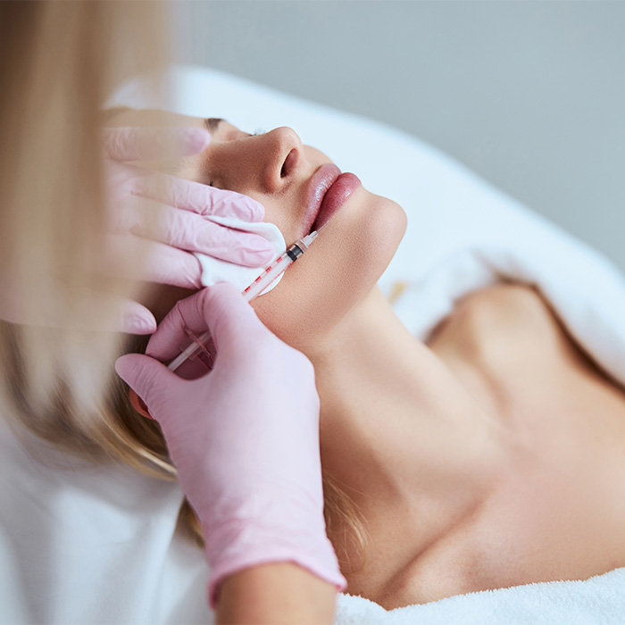A woman receiving a cosmetic procedure on her lips, illustrating the process and potential risks. A woman receiving a cosmetic procedure on her lips, illustrating the process and potential risks.
