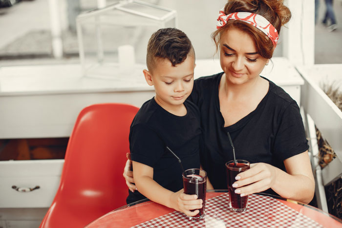 Woman and child with juice at a cafe, depicting an expensive phone incident. Woman and child with juice at a cafe, depicting an expensive phone incident.