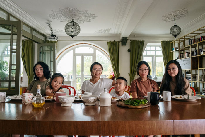 A family gathered around a dining table. The woman refuses to eat at MIL's home.