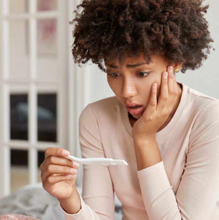 A surprised woman looks at a pregnancy test. Gynecologists provide crucial advice for women during pregnancy.