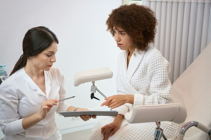 A woman in a medical robe discussing health concerns with a gynecologist, sharing valuable advice.