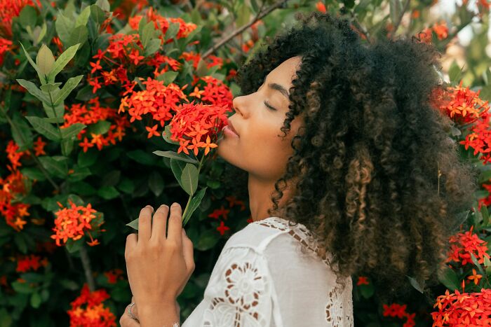A woman smelling a red flower, showing moments of peace inspired by advice from gynecologists.