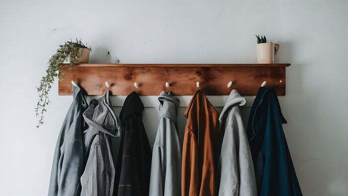 A coat rack with various coats hanging on it, illustrating house etiquette among guests.