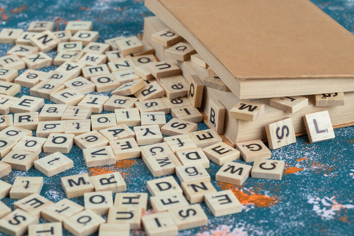 Scrabble tiles spilling from a book onto a textured surface, representing unsolved mysteries.