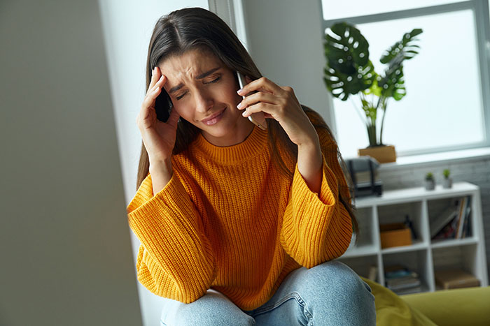 Slacking off at work: A distressed woman talking on the phone, experiencing stress from made-up bullying claims. Slacking off at work: A distressed woman talking on the phone, experiencing stress from made-up bullying claims.