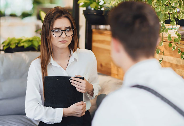 A young woman in glasses looking concerned while holding a clipboard, discussing made-up bullying claims. A young woman in glasses looking concerned while holding a clipboard, discussing made-up bullying claims.