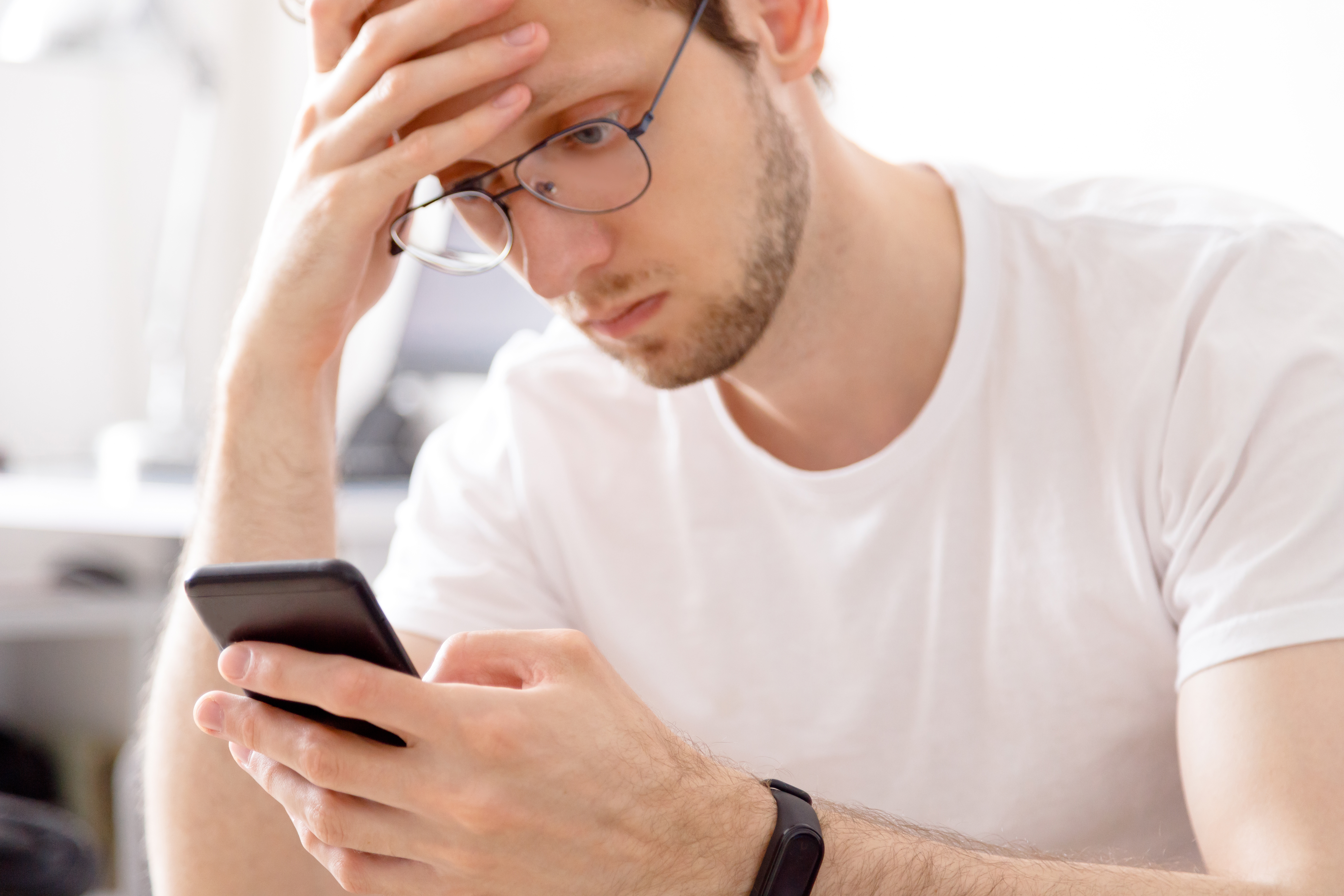 Guy sees something suspicious: A man with glasses, looking distressed, holds a phone.