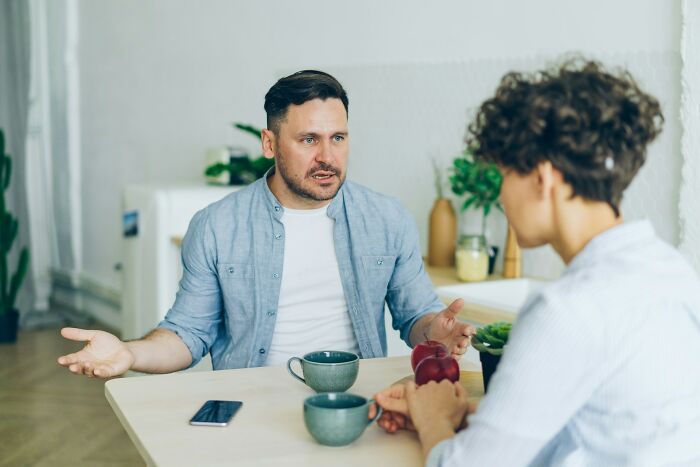 A man gesturing while talking to a woman, showing a potential first date red flag.