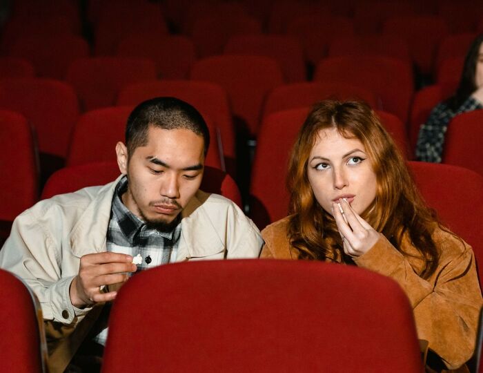 A man and a woman watching a movie in a cinema. Red flags on a first date could be bad manners in public.