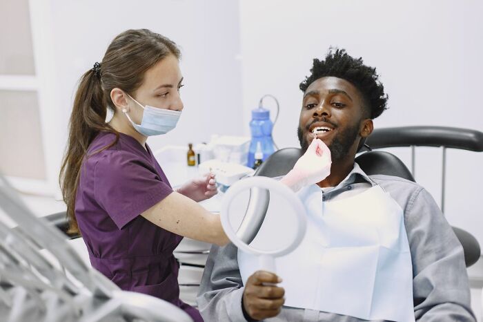 A man with a woman dentist looks in a mirror. A red flag on a first date could be poor hygiene.