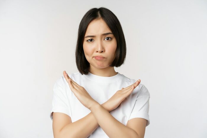 Woman making an X-sign with her arms, showing a clear first date red flag of disinterest or rejection.